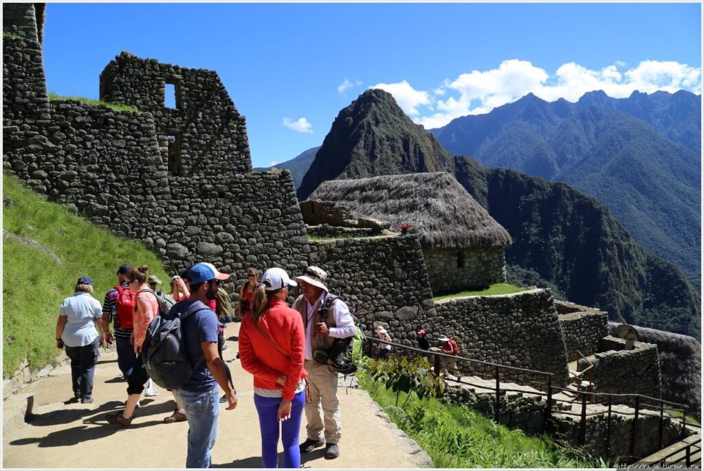 Local mountain guide showing a map to a small group at the beginning of a trail in Cusco