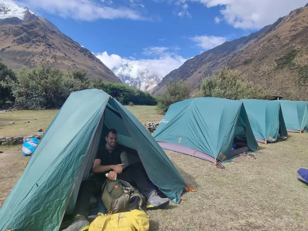 Trekker resting at high altitude camp with snow covered mountains in the background
