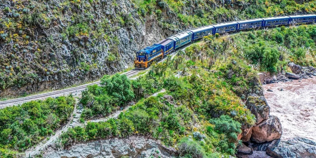 Train moving through misty cloud forest with waterfalls visible along the Urubamba River gorge