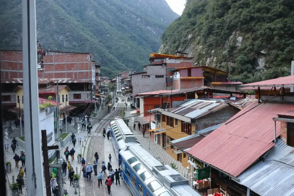 Train to Machu Picchu arriving at Aguas Calientes at sunrise with mountain backdrop
