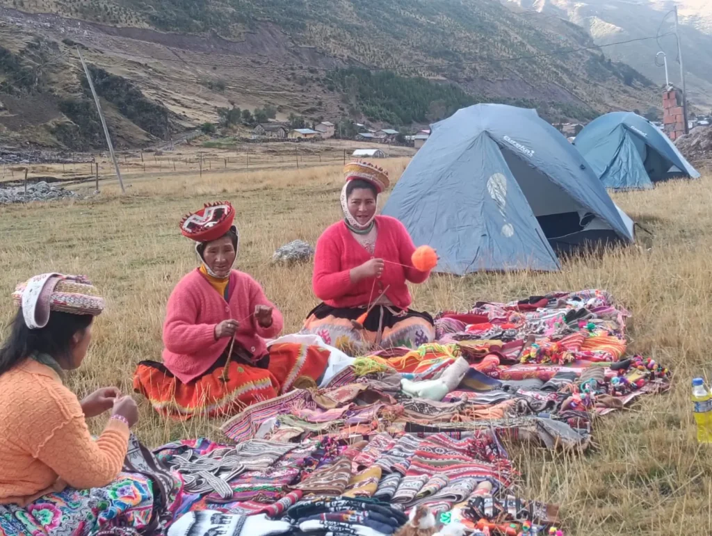 Lares Trek traditional Quechua village with colorful textiles and snow-capped mountains behind