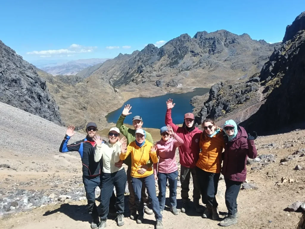 Lares Trek trekker standing at the mountain pass at 4,400 meters with panoramic Andean views