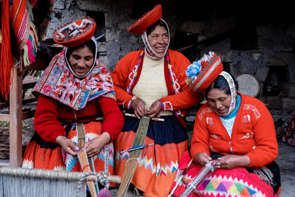 Quechua woman in traditional colorful clothing weaving textiles in a remote Andean village